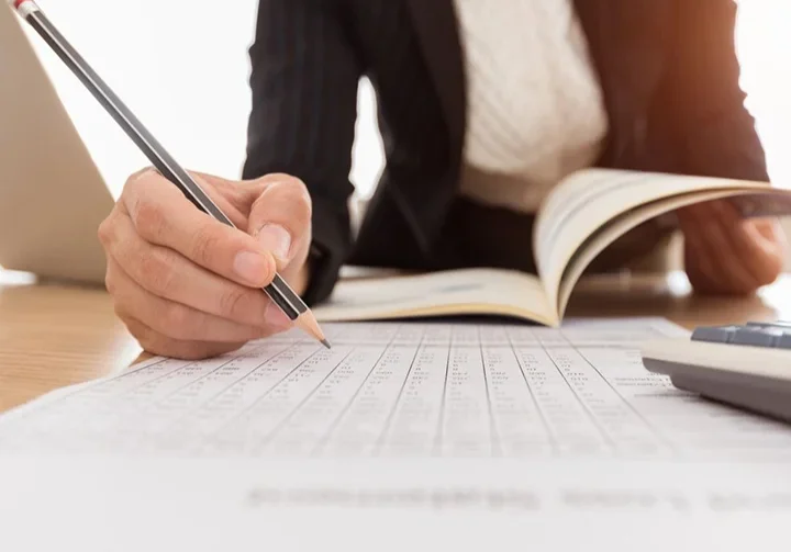 A person writing on paper with a pencil