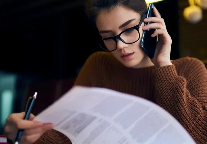 A woman is on her cell phone and reading.